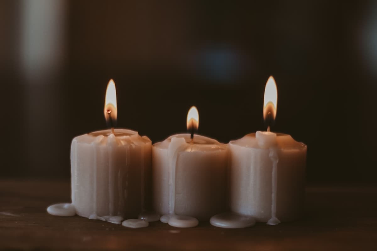 Three melting pillar candles with warm glow